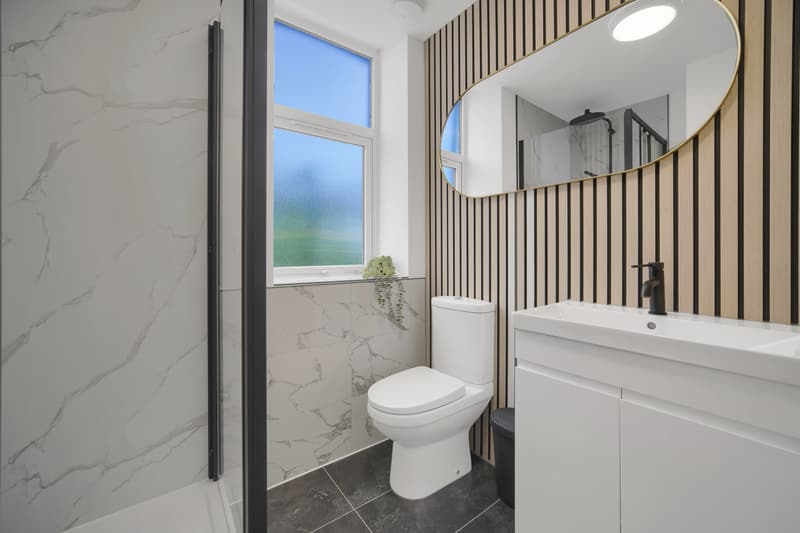 Bathroom with marble-effect tiles, oak slat panelling and round mirror